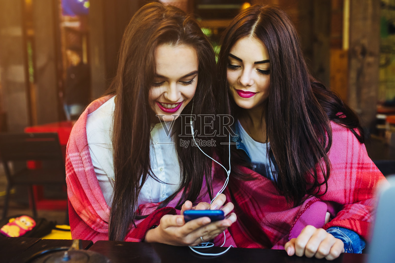 两个女孩坐着听手机音乐照片摄影图片