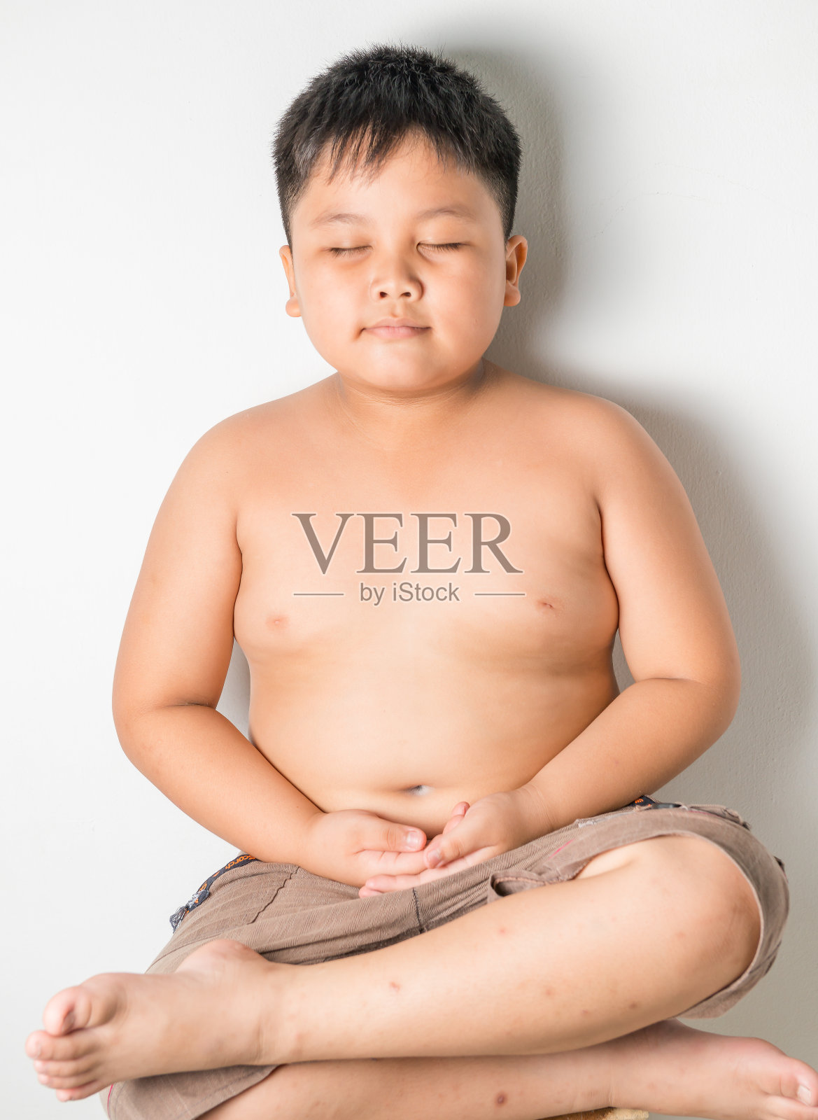 胖男孩在椅子上莲花坐姿沉思照片摄影图片