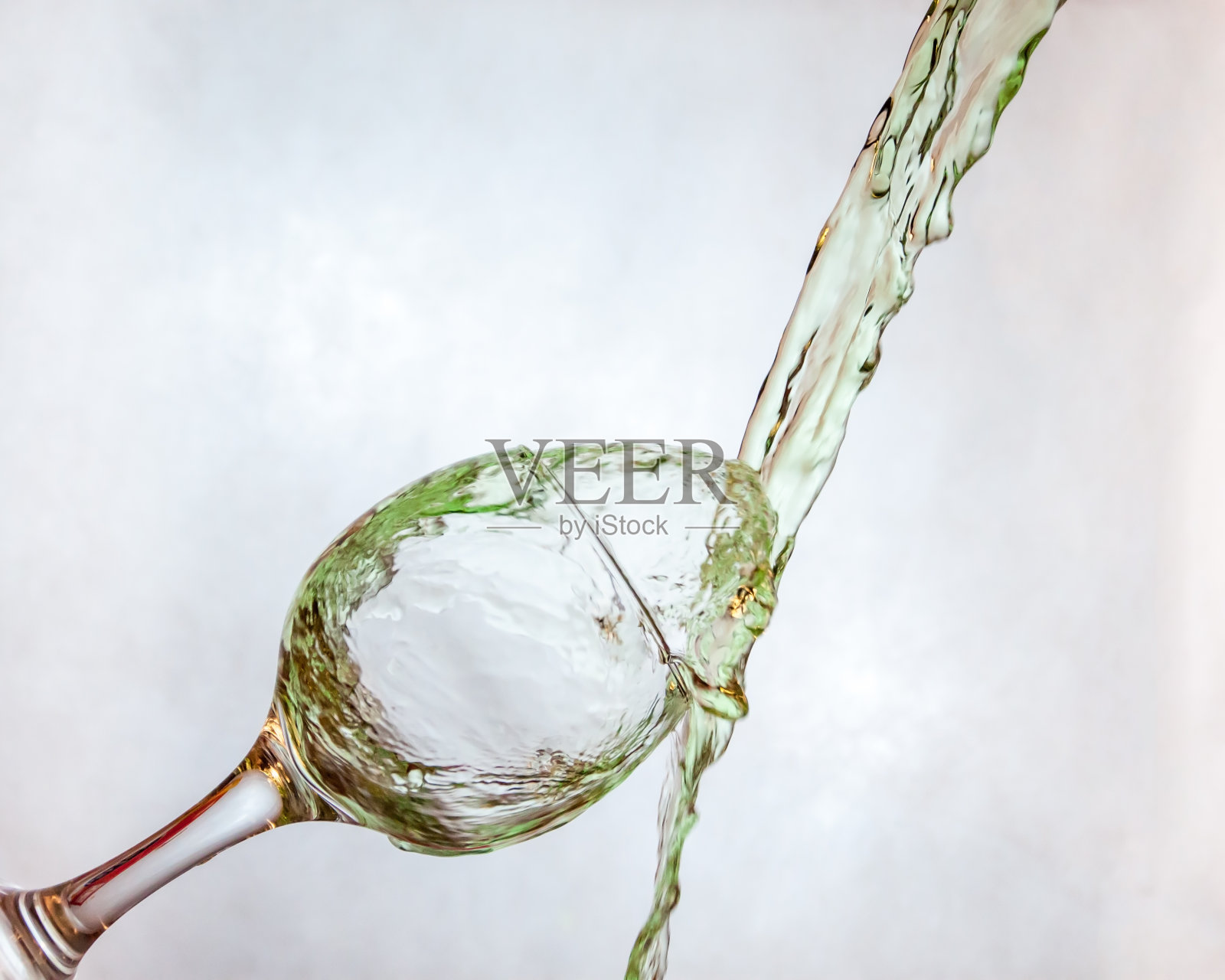 向葡萄酒杯中倒入彩色的水照片摄影图片