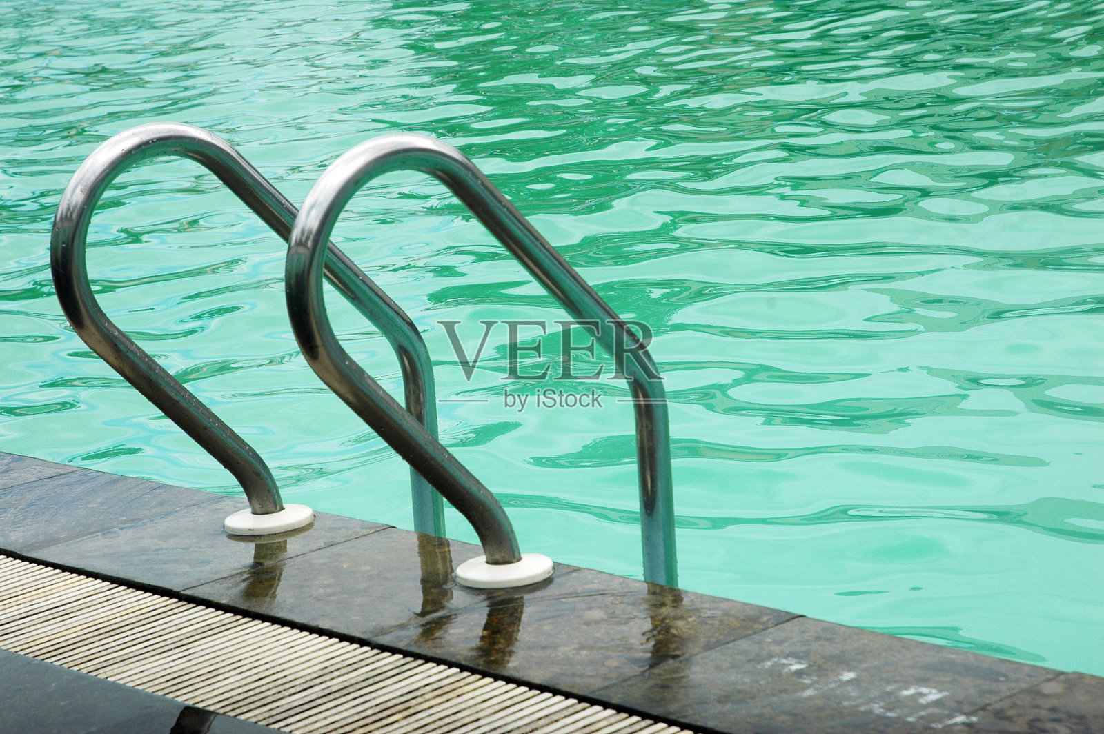 游泳池内的不锈钢梯子照片摄影图片