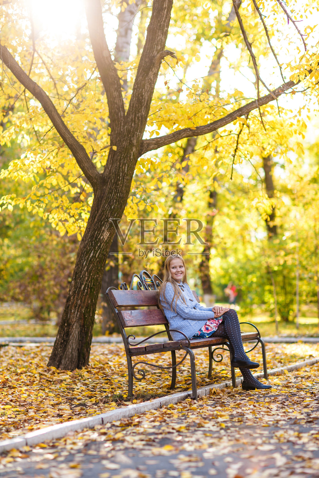 秋天，女孩坐在公园的长椅上照片摄影图片