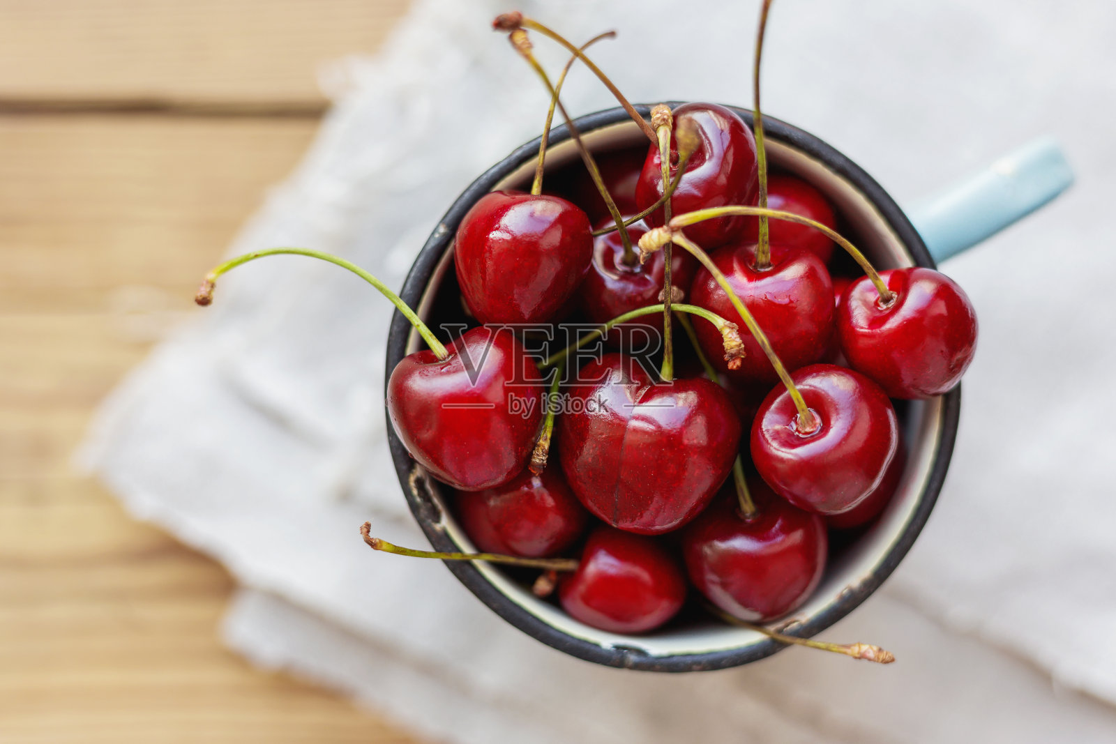 新鲜多汁的甜樱桃放在生锈的杯子里。乡村背景照片摄影图片