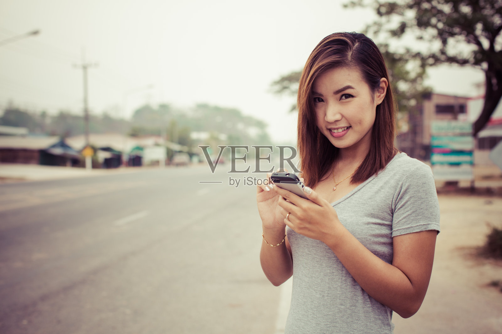 女孩用智能手机开心的在路上照片摄影图片
