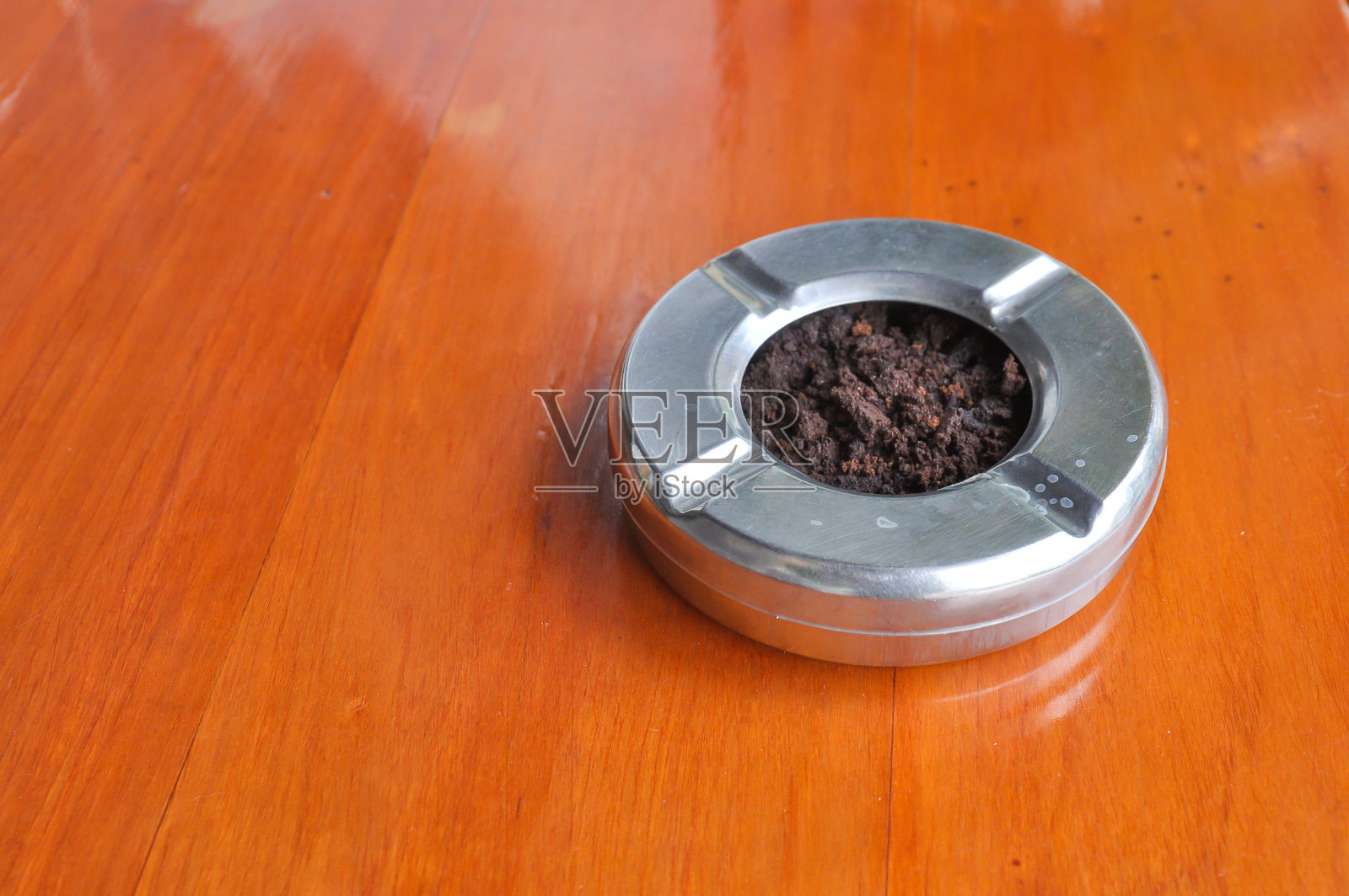 木桌上的不锈钢烟灰缸照片摄影图片