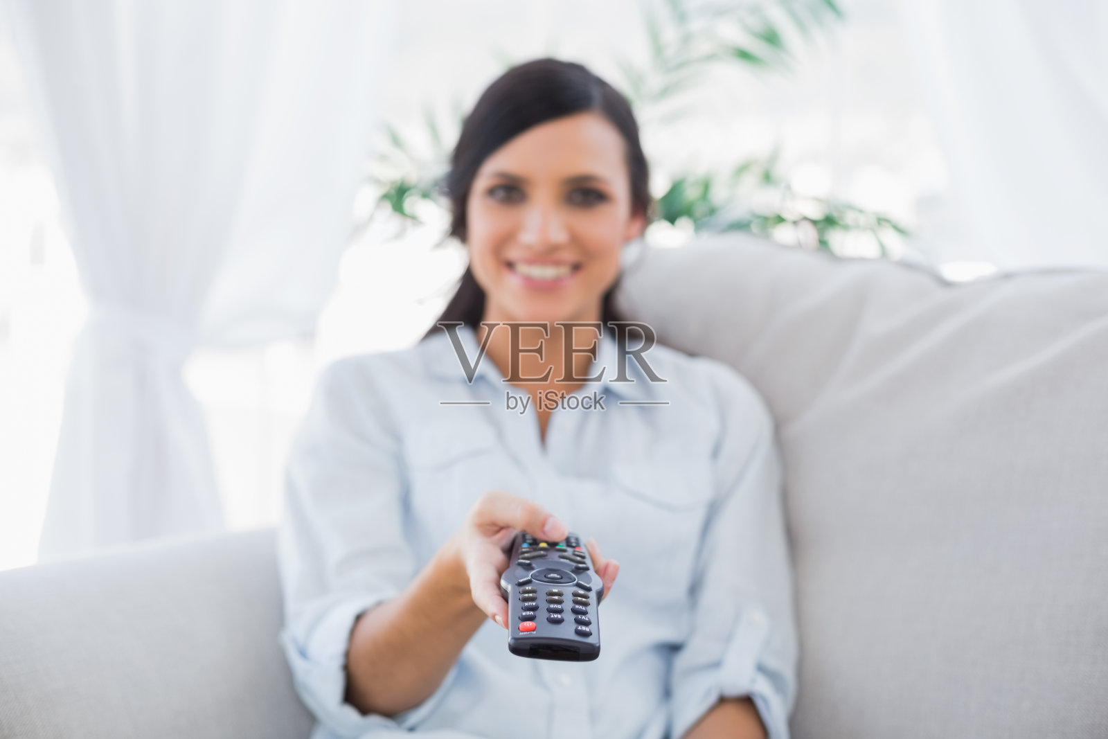 开朗迷人的黑发女人变换电视频道照片摄影图片