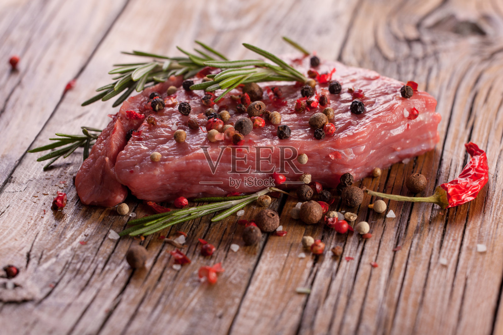 深色的木桌上放着生牛排。照片摄影图片