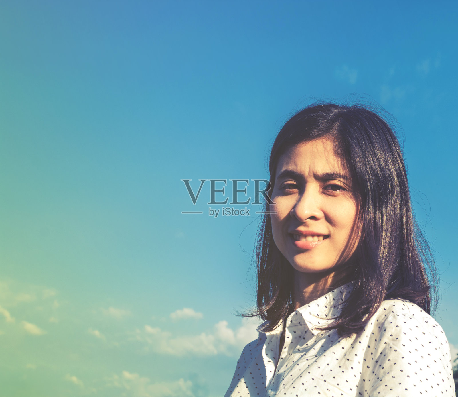 美丽的亚洲女人在蓝天下微笑的肖像照片摄影图片