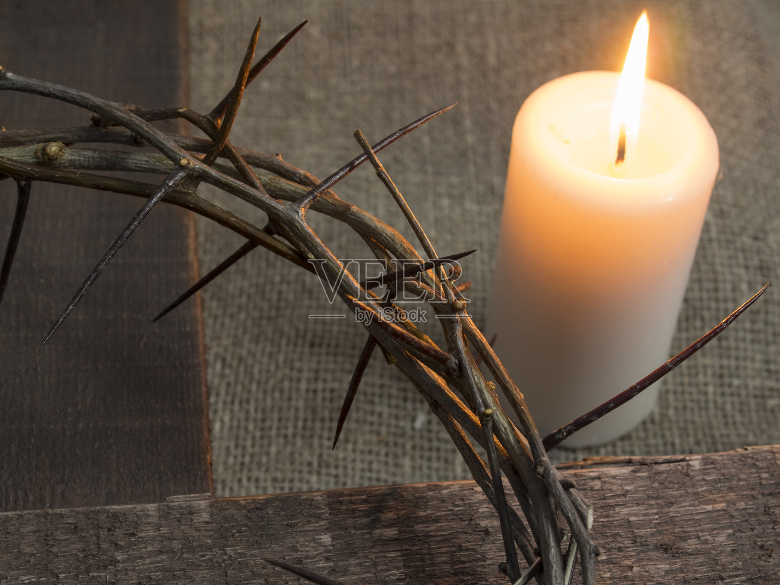 木头十字架上的荆棘王冠和燃烧的蜡烛。照片摄影图片