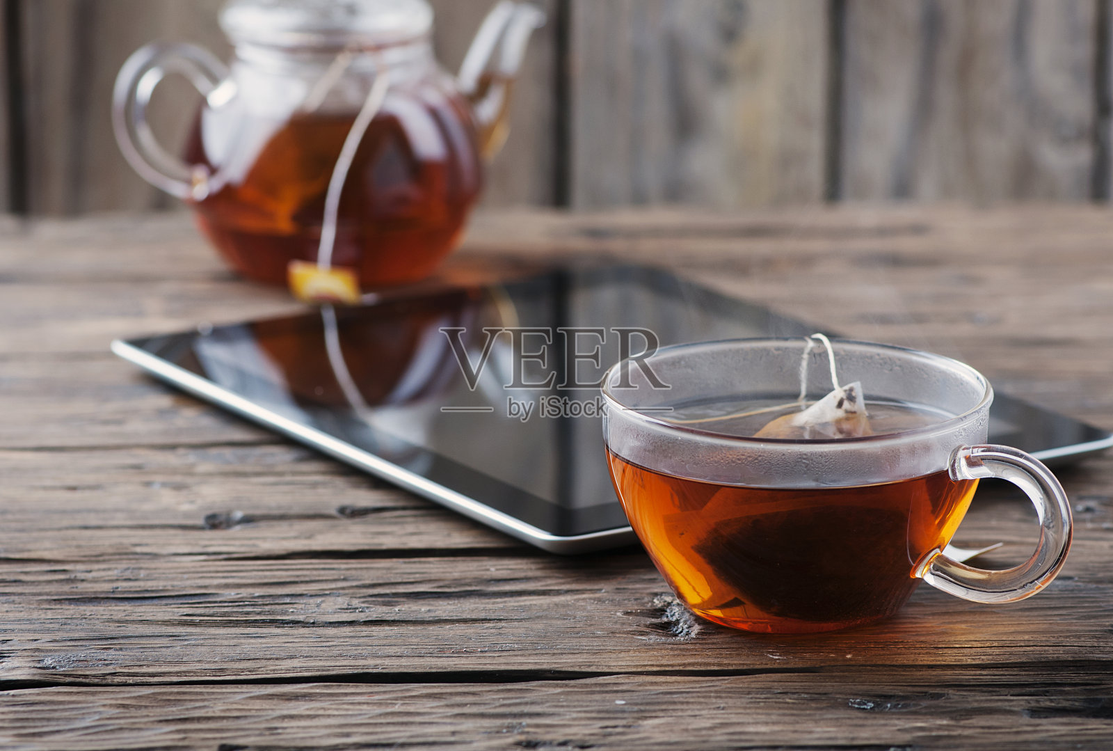 旧木桌上放着数码平板和一杯茶照片摄影图片