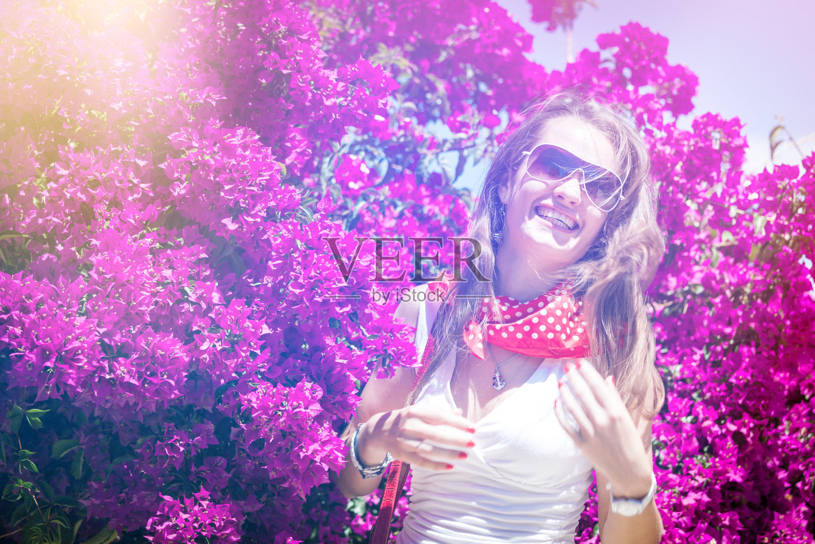 女孩在阳光下的花背景上笑照片摄影图片