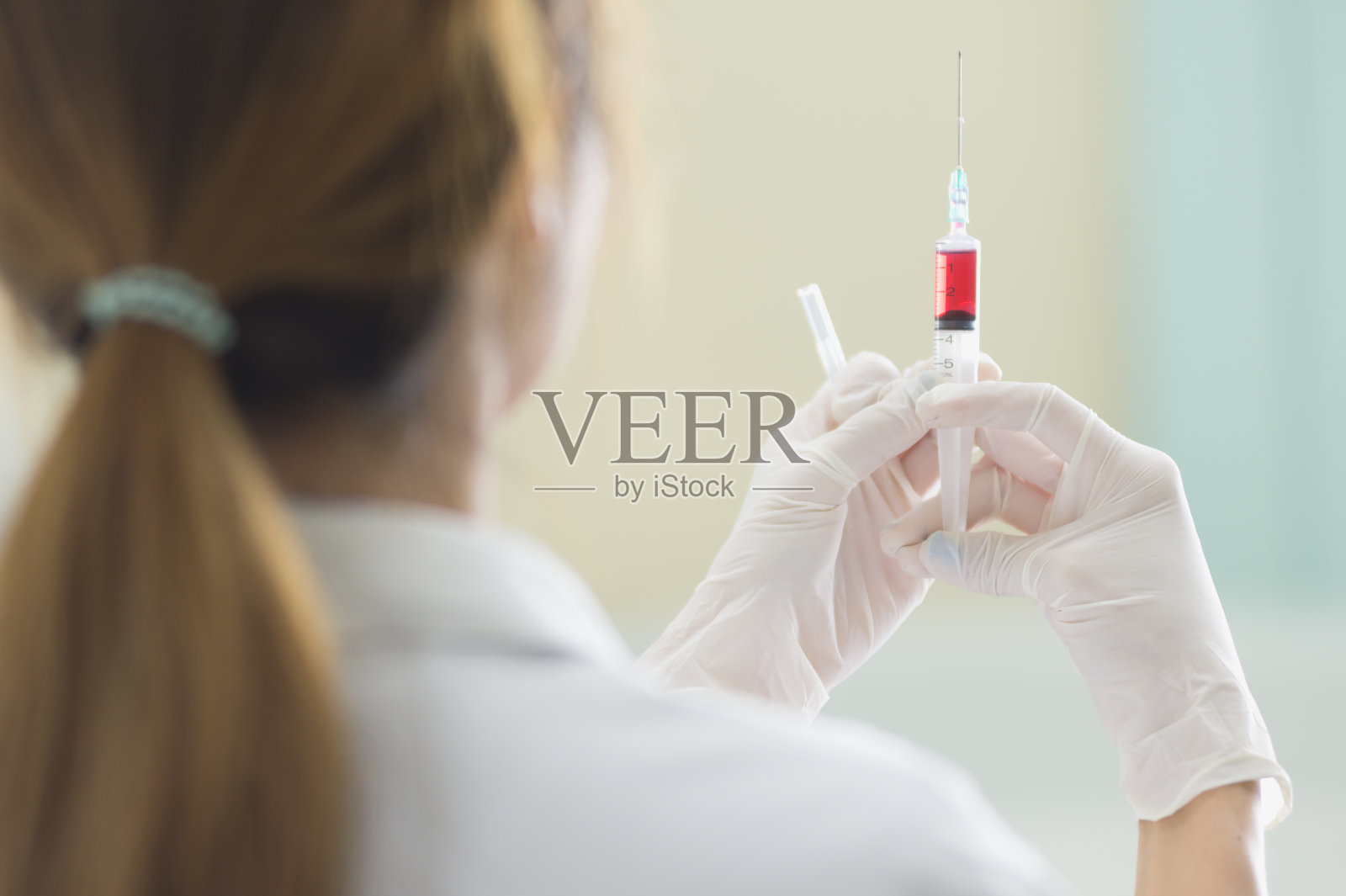 医生手里拿着红色的疫苗注射器照片摄影图片