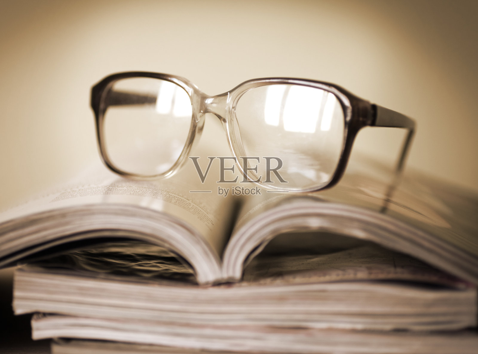 在一堆杂志上看书用的眼镜照片摄影图片
