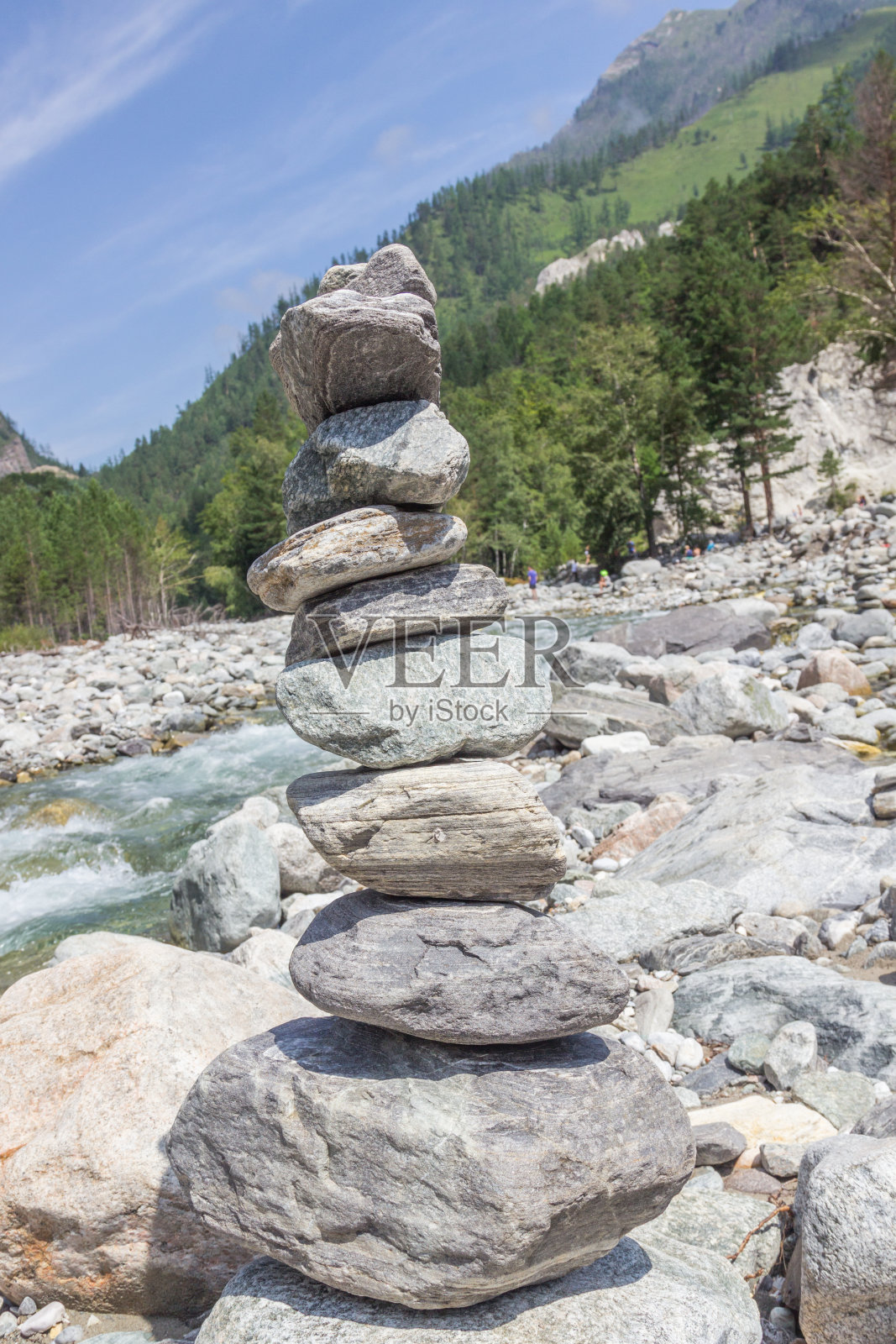 金字塔由石头砌在河堤上，背靠山景。照片摄影图片