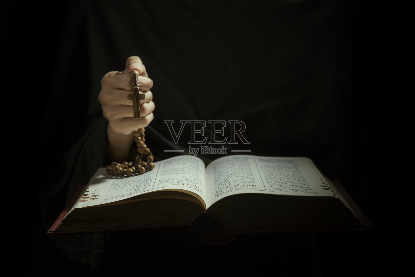 圣经打开，手上有个十字架照片摄影图片