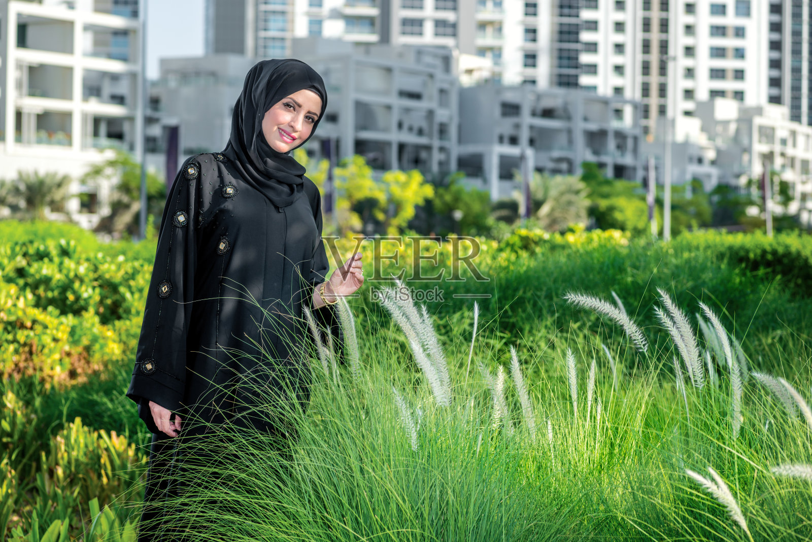 阿拉伯式的生活。戴着头巾的阿拉伯女商人走在街上照片摄影图片