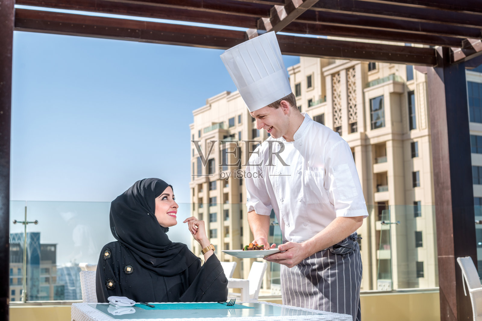 餐厅服务。厨师为戴着头巾的阿拉伯女性服务照片摄影图片