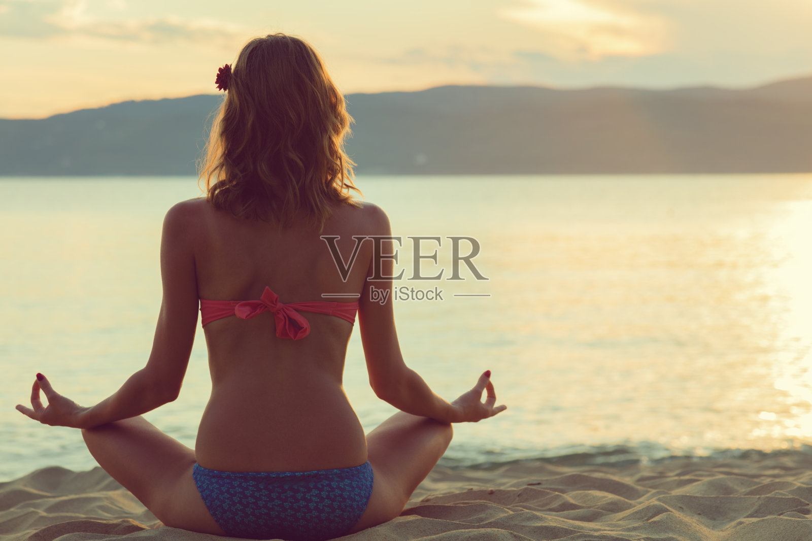 年轻女子在海滩上练习瑜伽。照片摄影图片