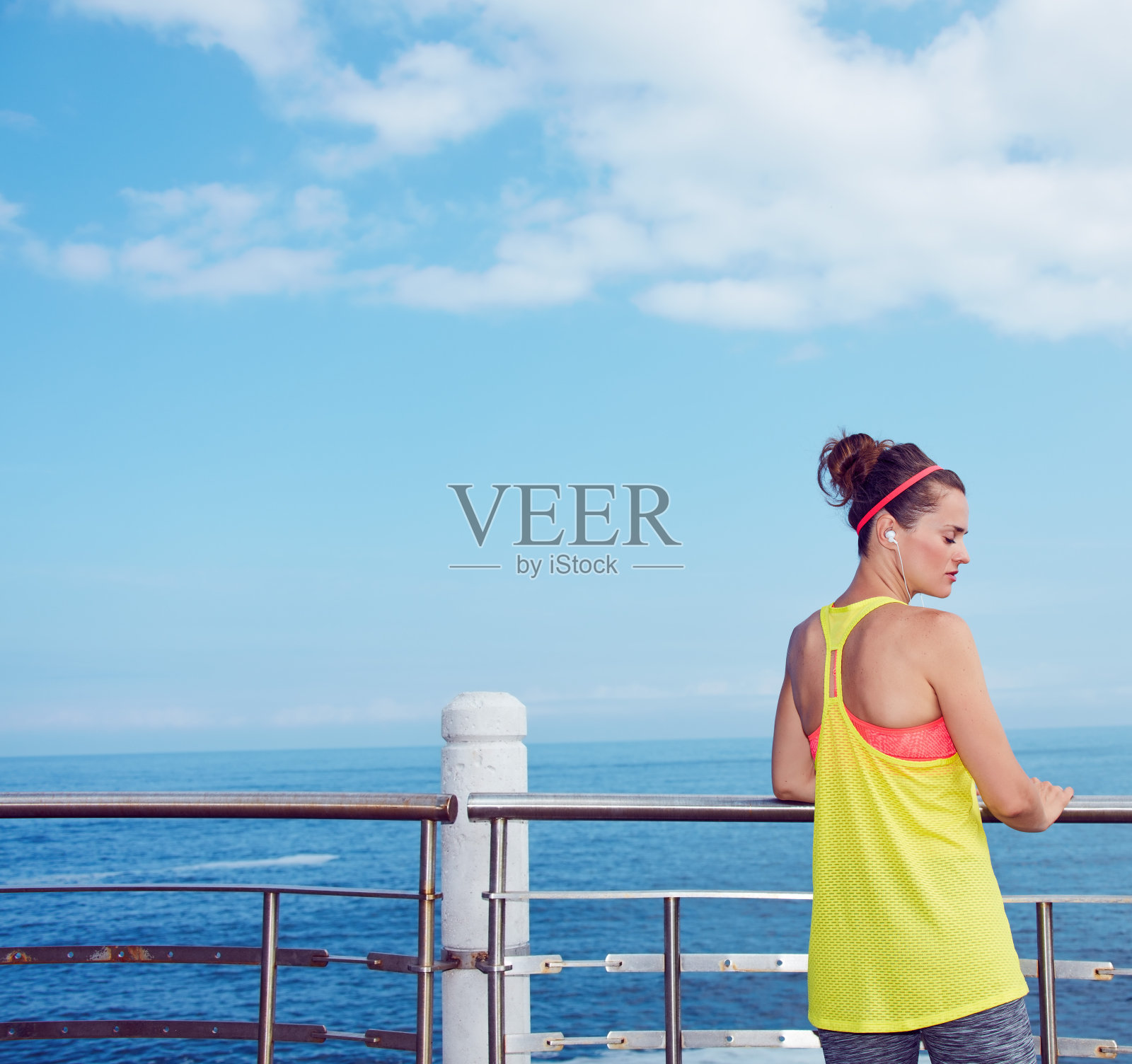 穿着健身服的年轻运动员站在河堤上照片摄影图片