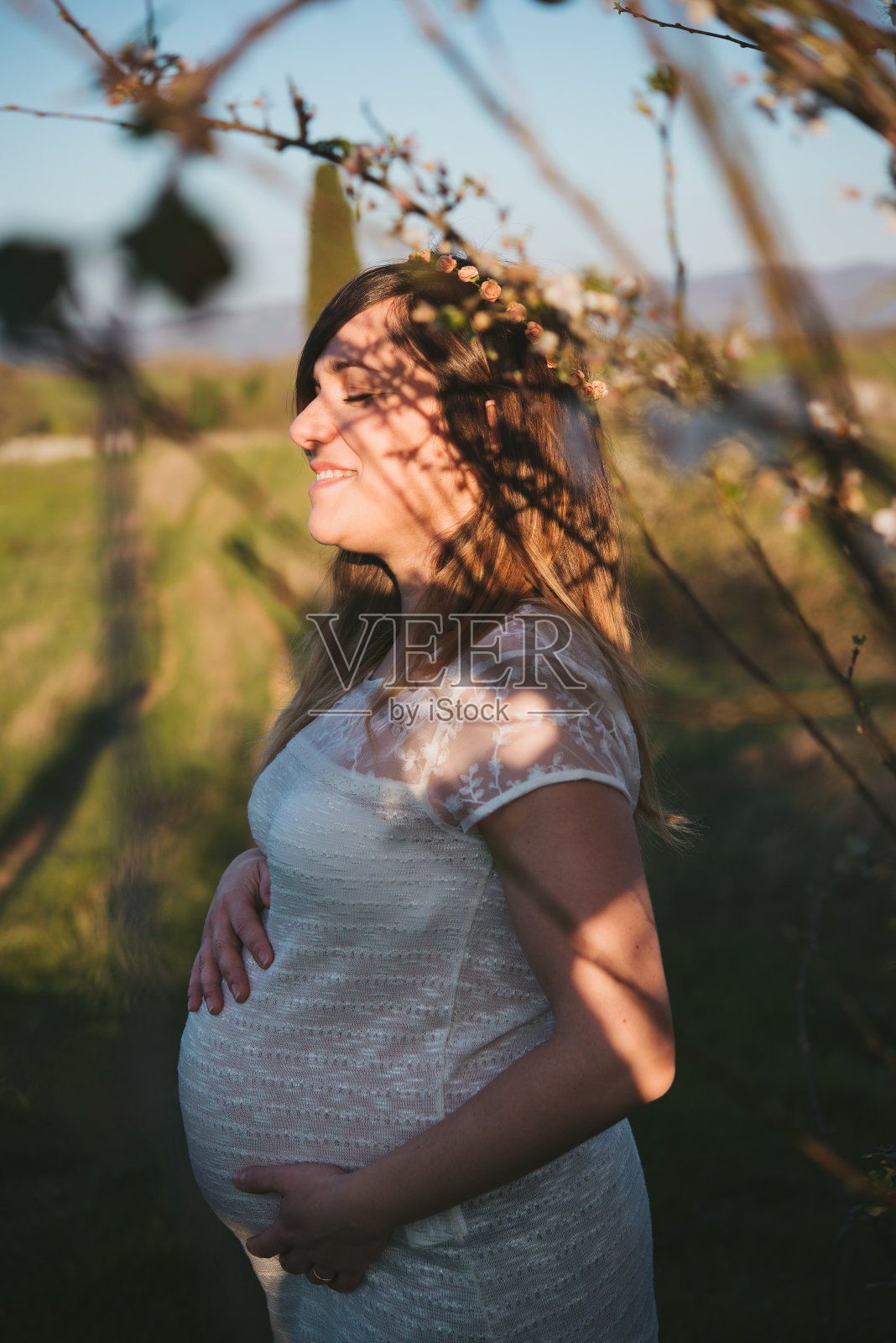 微笑的孕妇肖像走进大自然，春天照片摄影图片