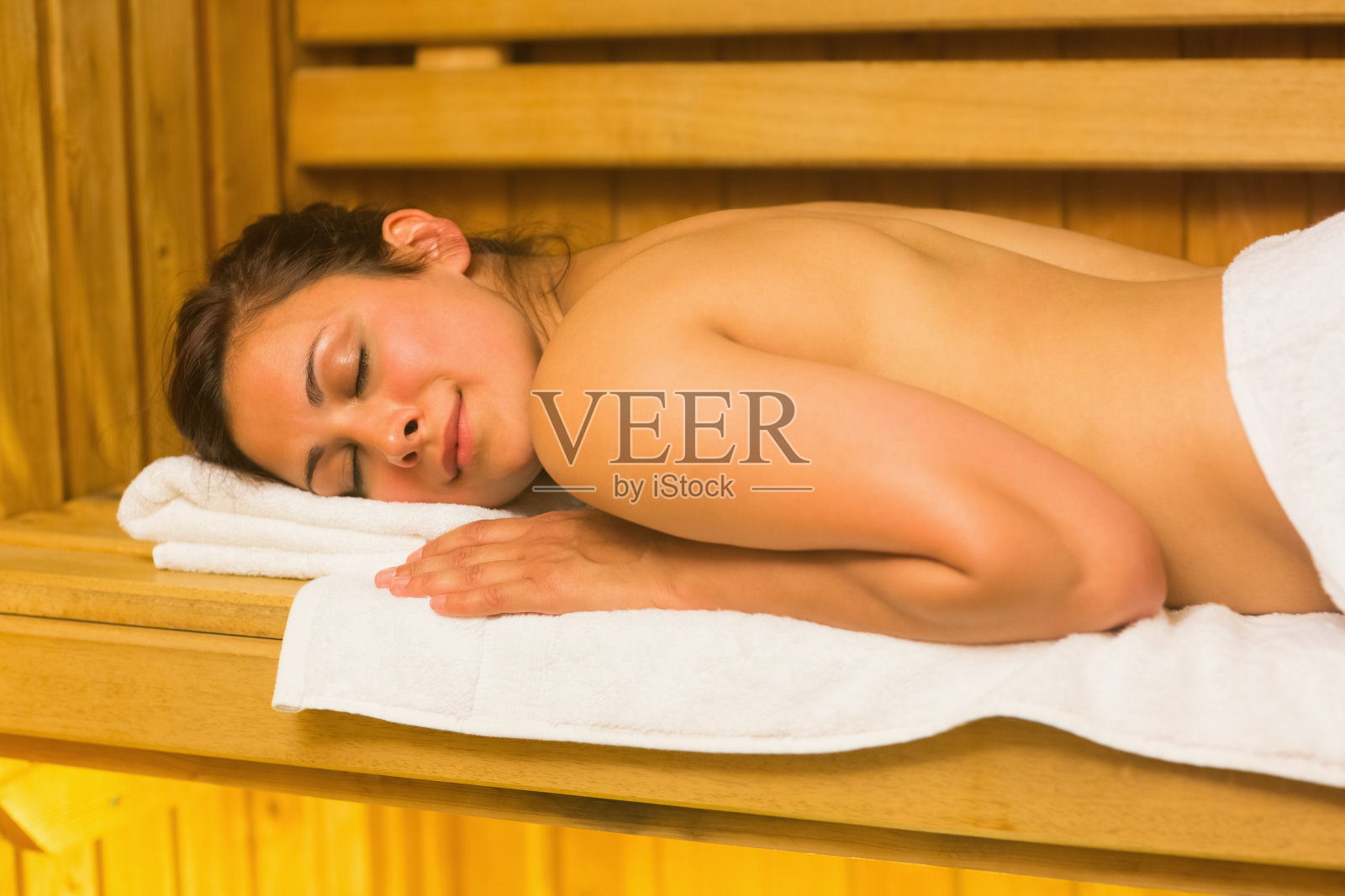 快乐的黑发女子躺在桑拿房里照片摄影图片