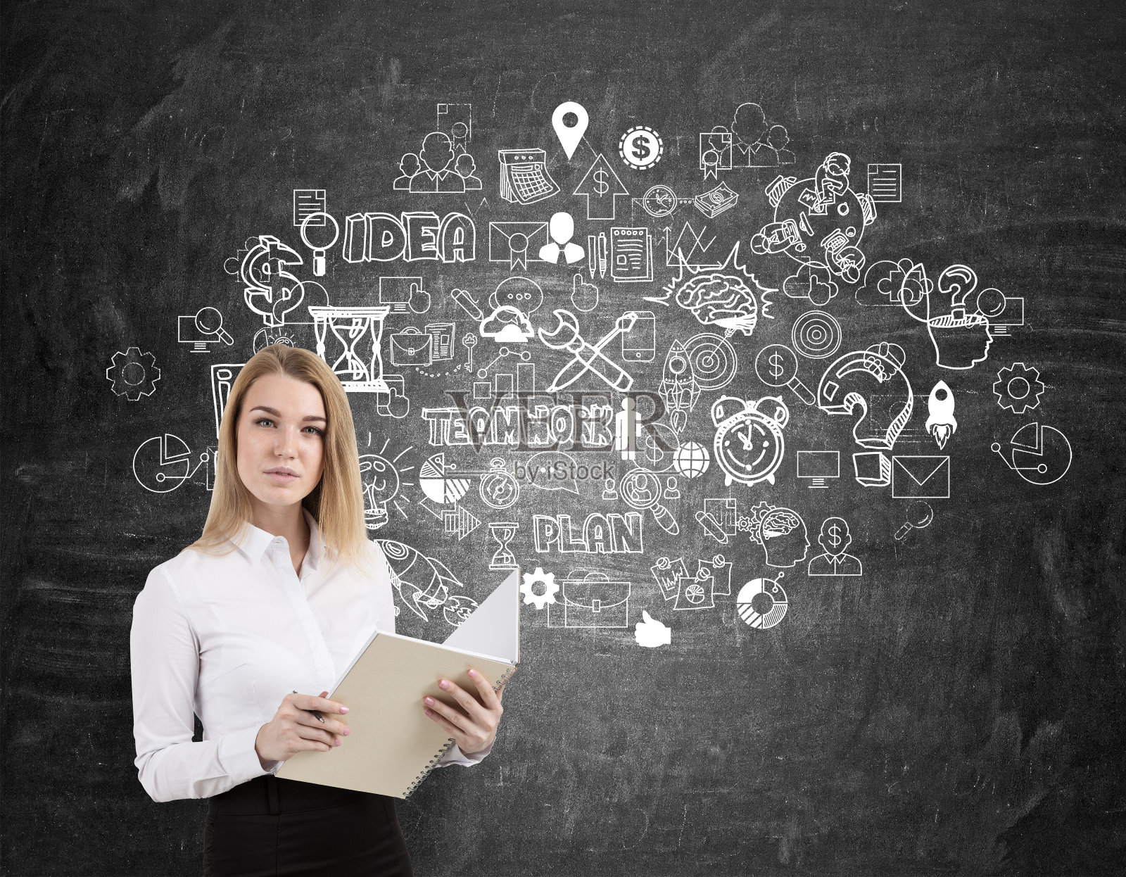 金发女人拿着笔记本在黑板上画着团队草图照片摄影图片