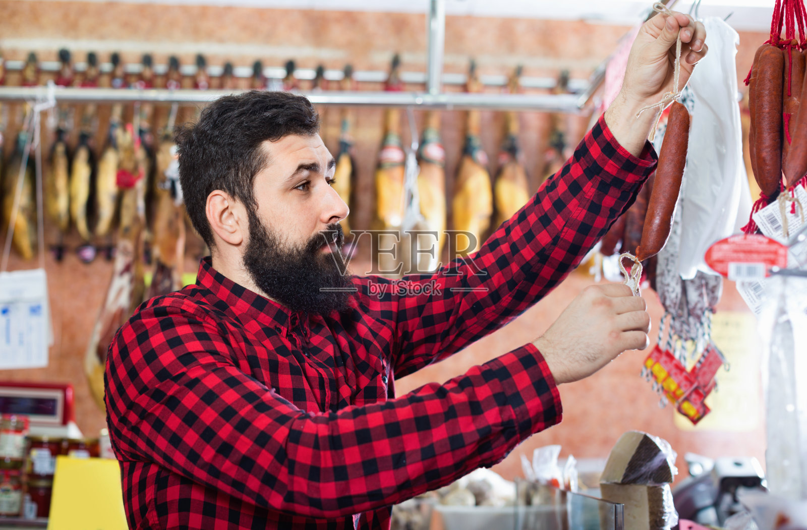 一位年轻的男顾客正在butcherâ的店里检查香肠照片摄影图片