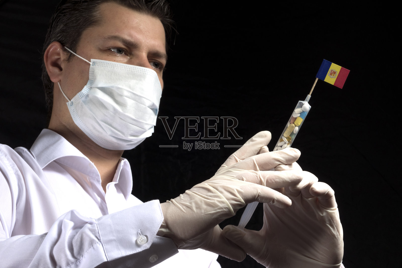 一名年轻男子作为一名医生，正在给黑色背景上的安道尔国旗进行医疗注射照片摄影图片