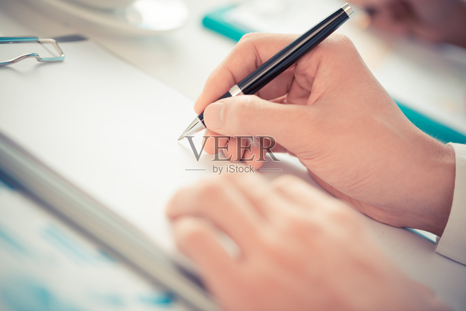 手拿着笔放在写字板上照片摄影图片