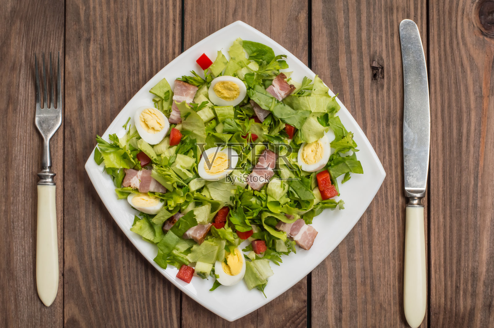 菠菜，鹌鹑蛋和培根沙拉。木制的桌子。前照片摄影图片