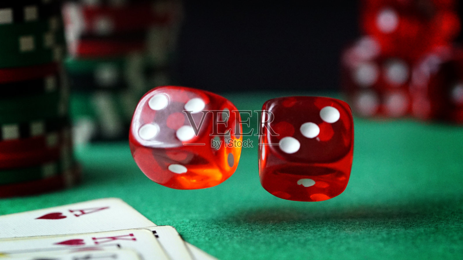 红色骰子，赌场筹码，绿色毛毡上的牌照片摄影图片