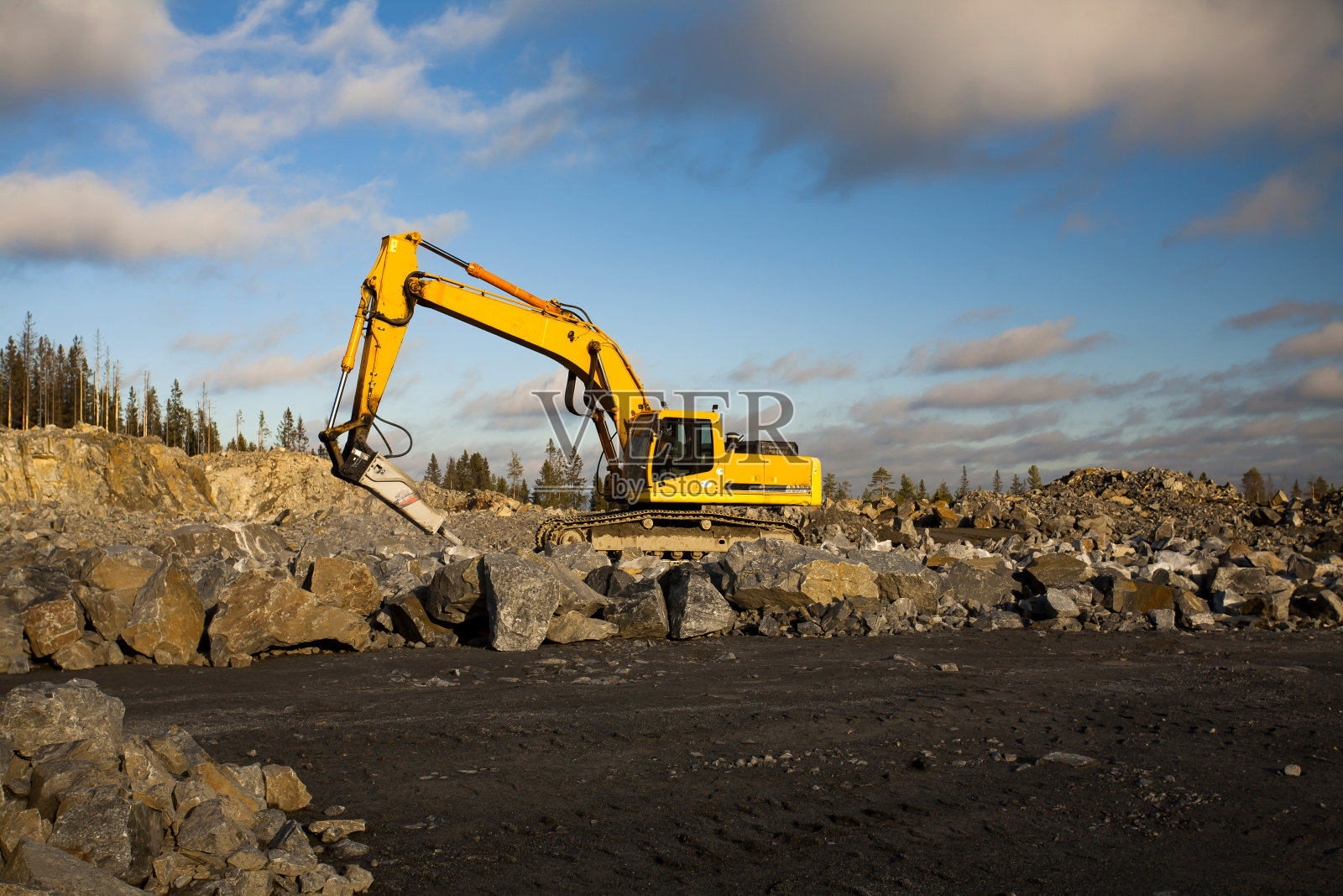 在砂石坑中作业的液压锤挖掘机照片摄影图片