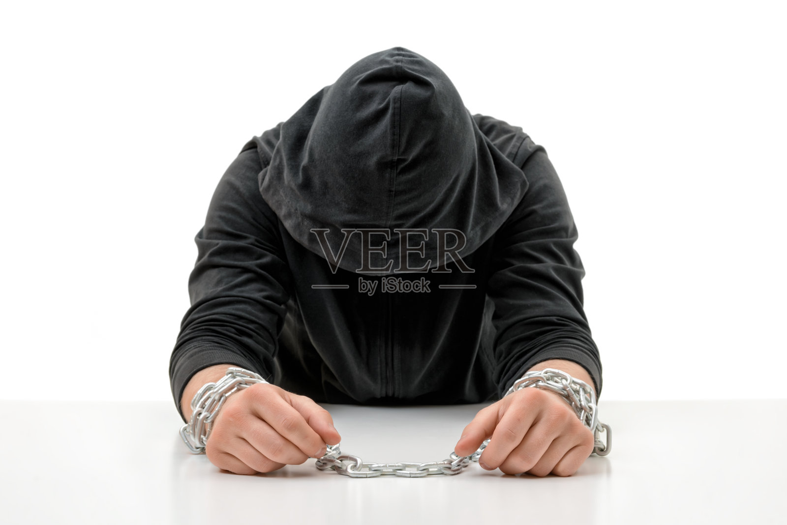 手被铁链锁着的人正低着头坐着照片摄影图片