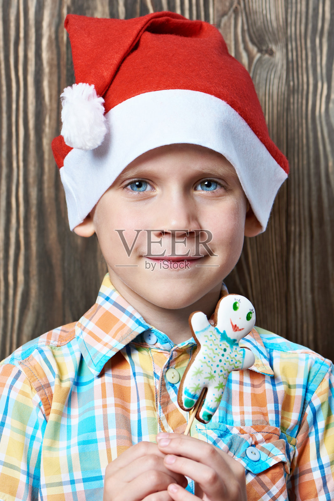 小男孩戴着红帽子，吃着圣诞饼干照片摄影图片