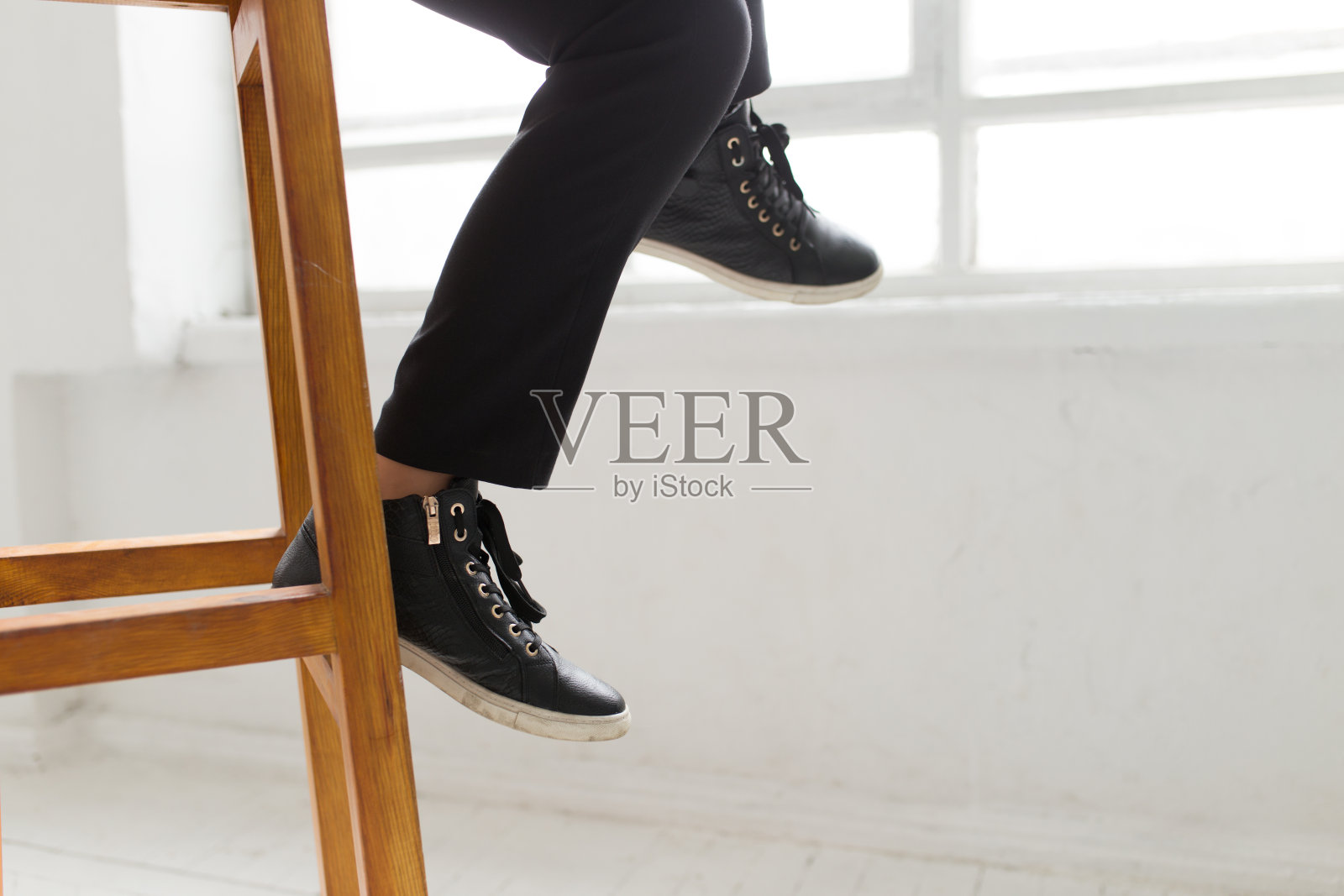简洁的风格——女人穿着侦探鞋坐在木凳上照片摄影图片