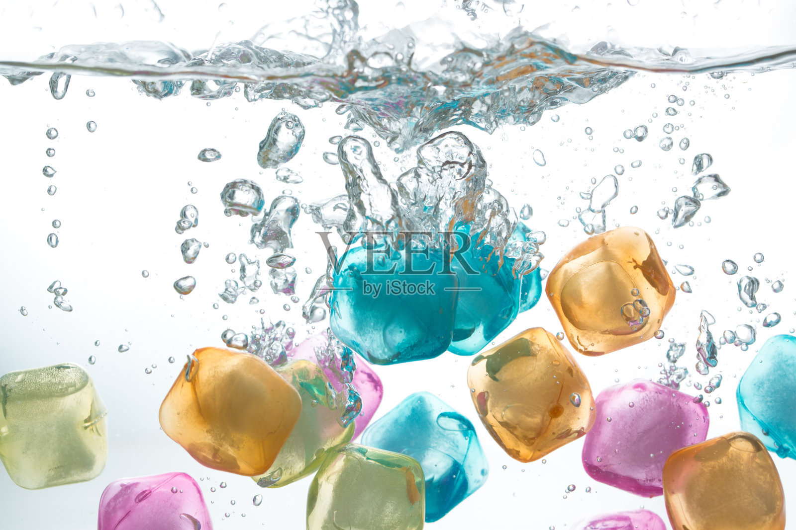 五颜六色的冰块落入水中。照片摄影图片