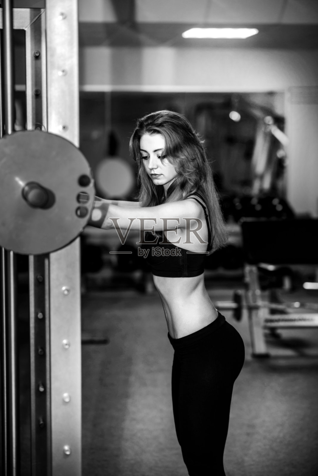 年轻漂亮的女孩在健身房锻炼照片摄影图片