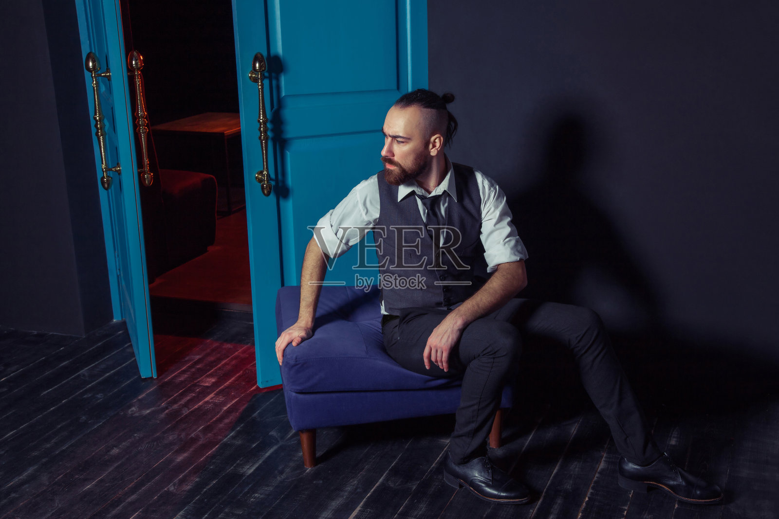 穿着西装的时装模特靠近红光闪烁的门。照片摄影图片