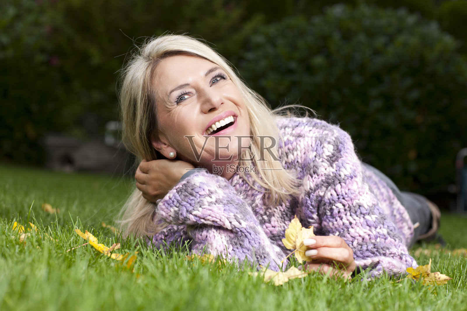 迷人的成熟女子躺在秋天的草地上照片摄影图片