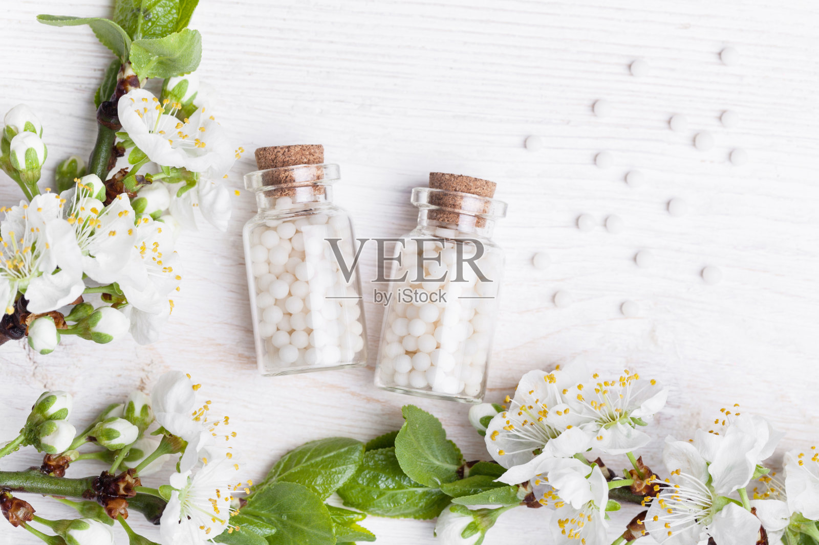 顺势疗法药丸与春天的花在白色木制背景照片摄影图片