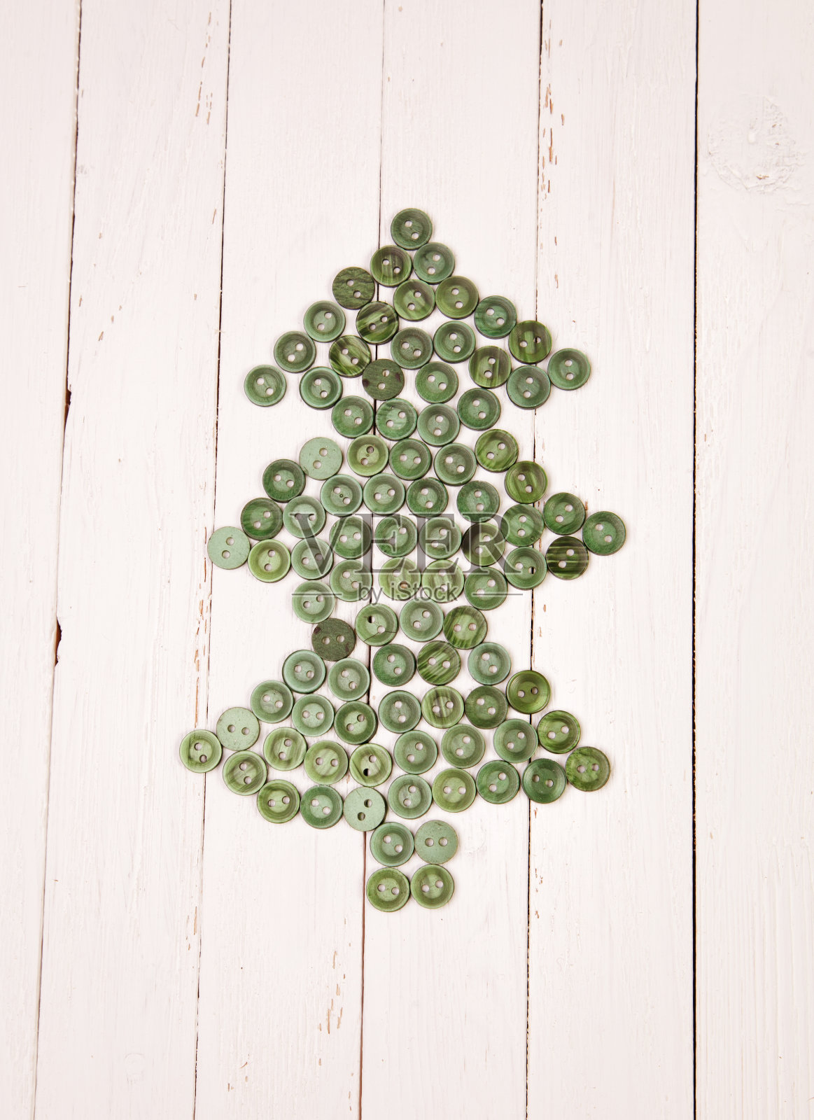圣诞树上的纽扣放在白色背景的木桌上照片摄影图片