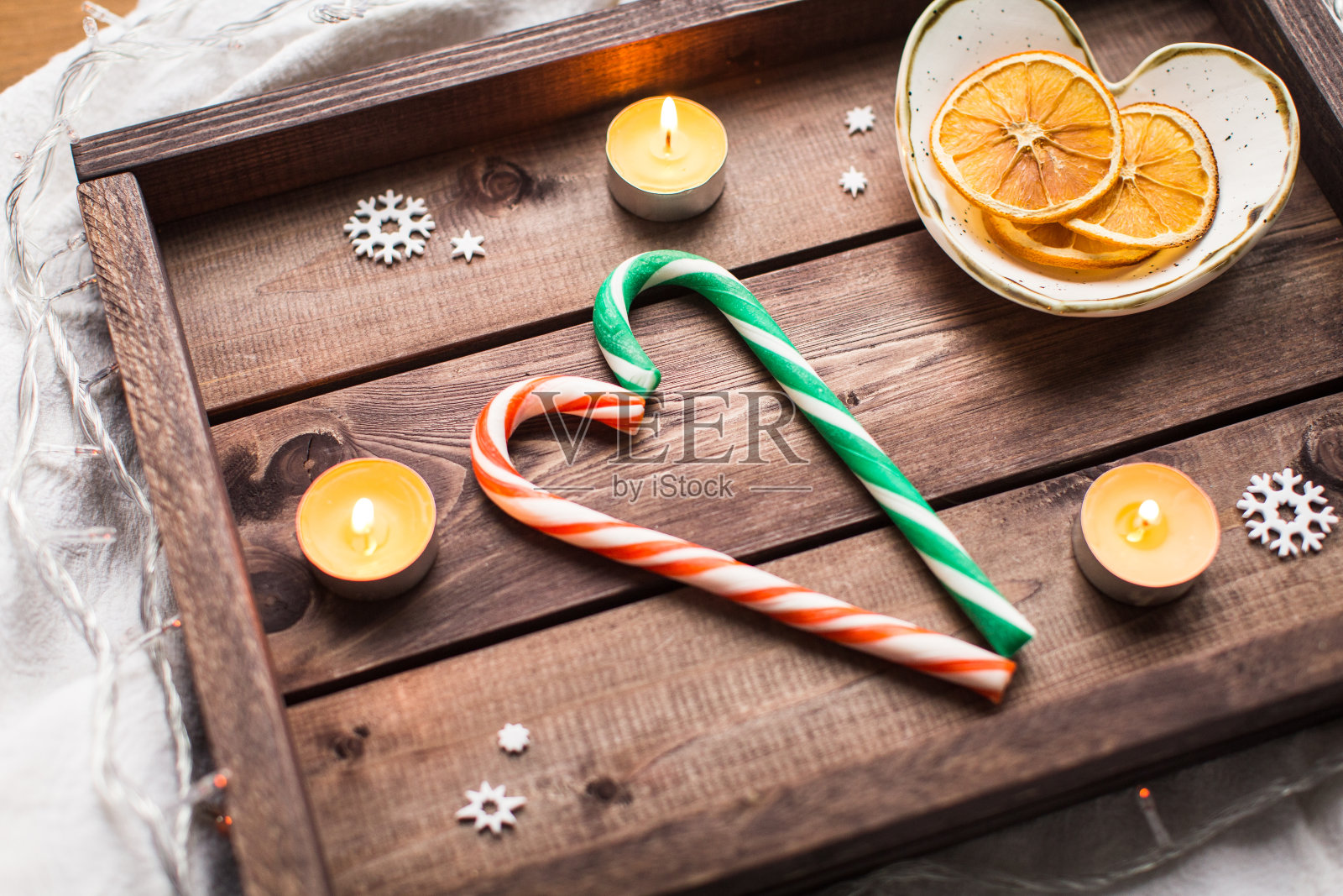圣诞木托盘上放着蜡烛、糖果和橙子照片摄影图片