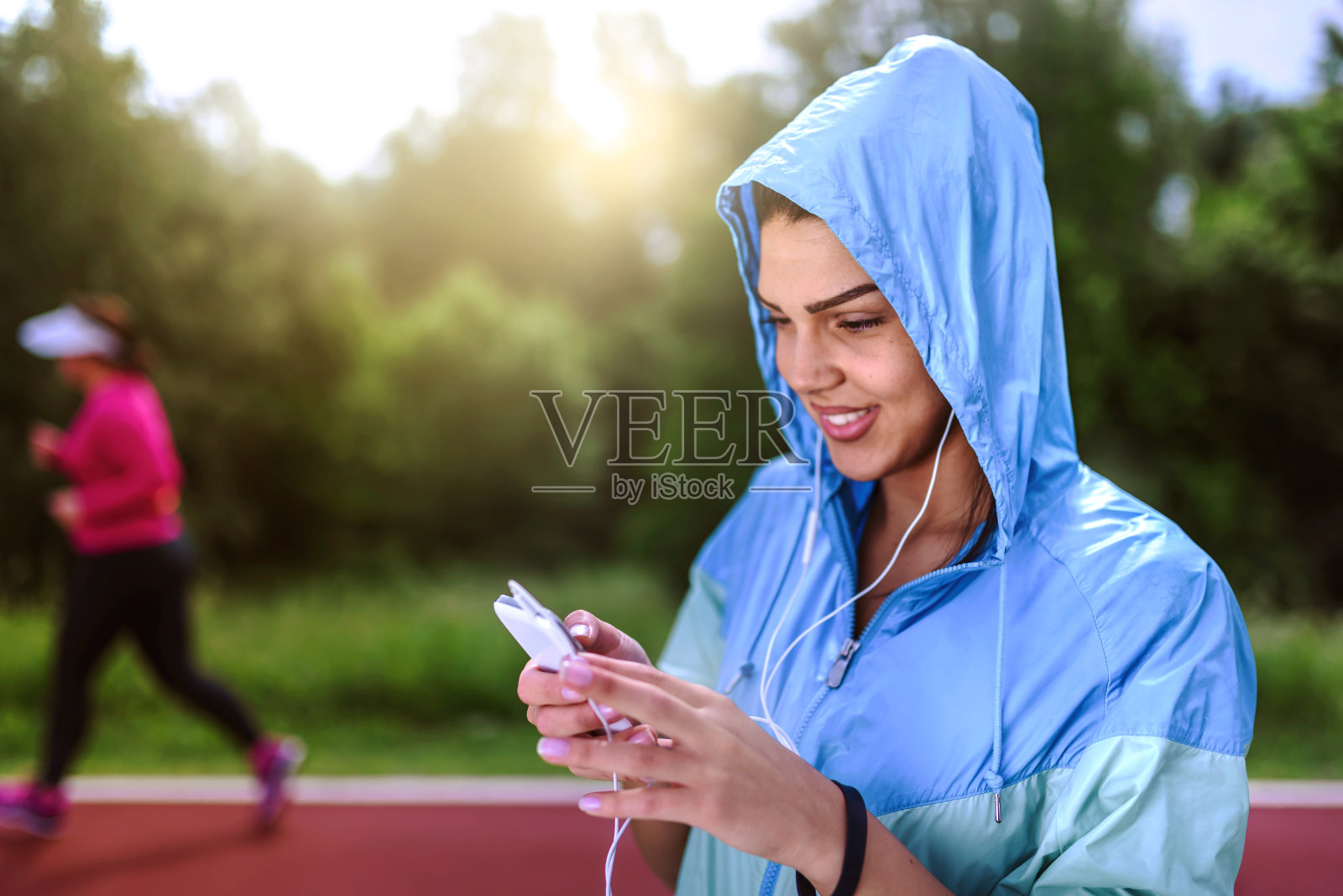 带着耳机和雨衣的慢跑女孩照片摄影图片