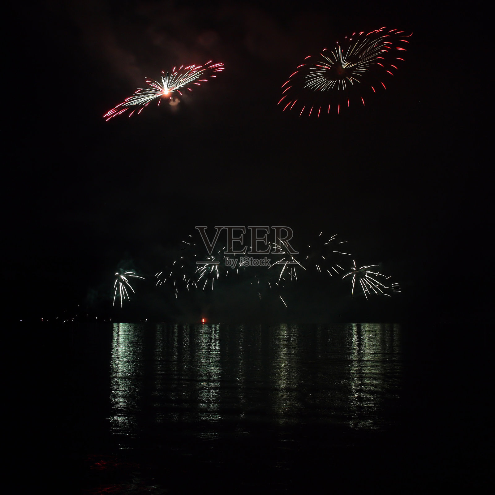 五彩缤纷的烟花映在湖面上。照片摄影图片