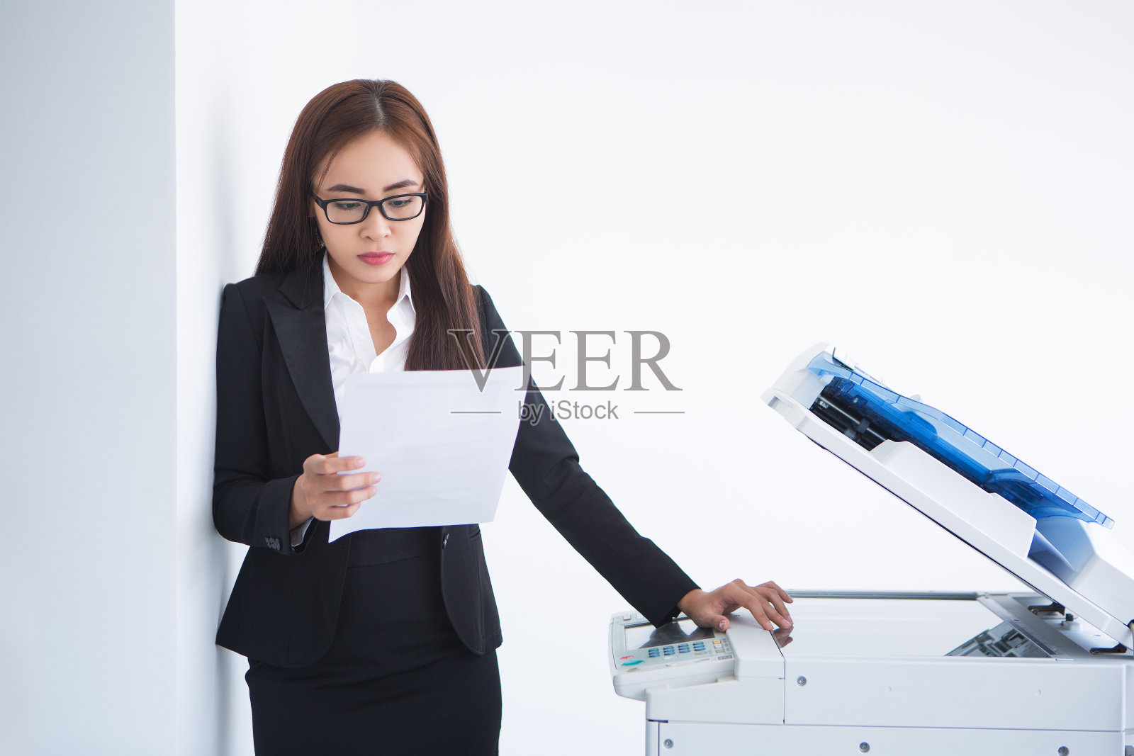 亚洲商务女性在复印机前阅读文件照片摄影图片