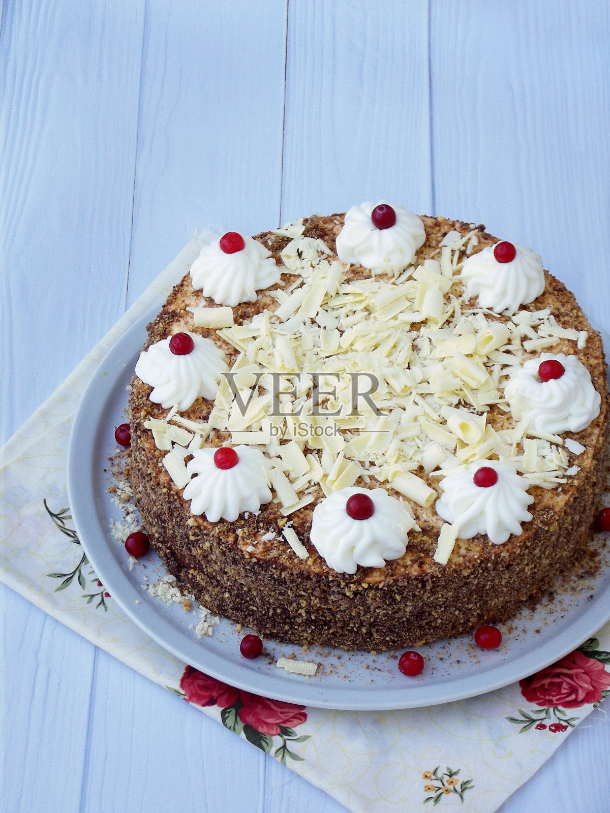 巧克力蛋糕，以奶油和浆果的花环装饰在木制的背景上。照片摄影图片