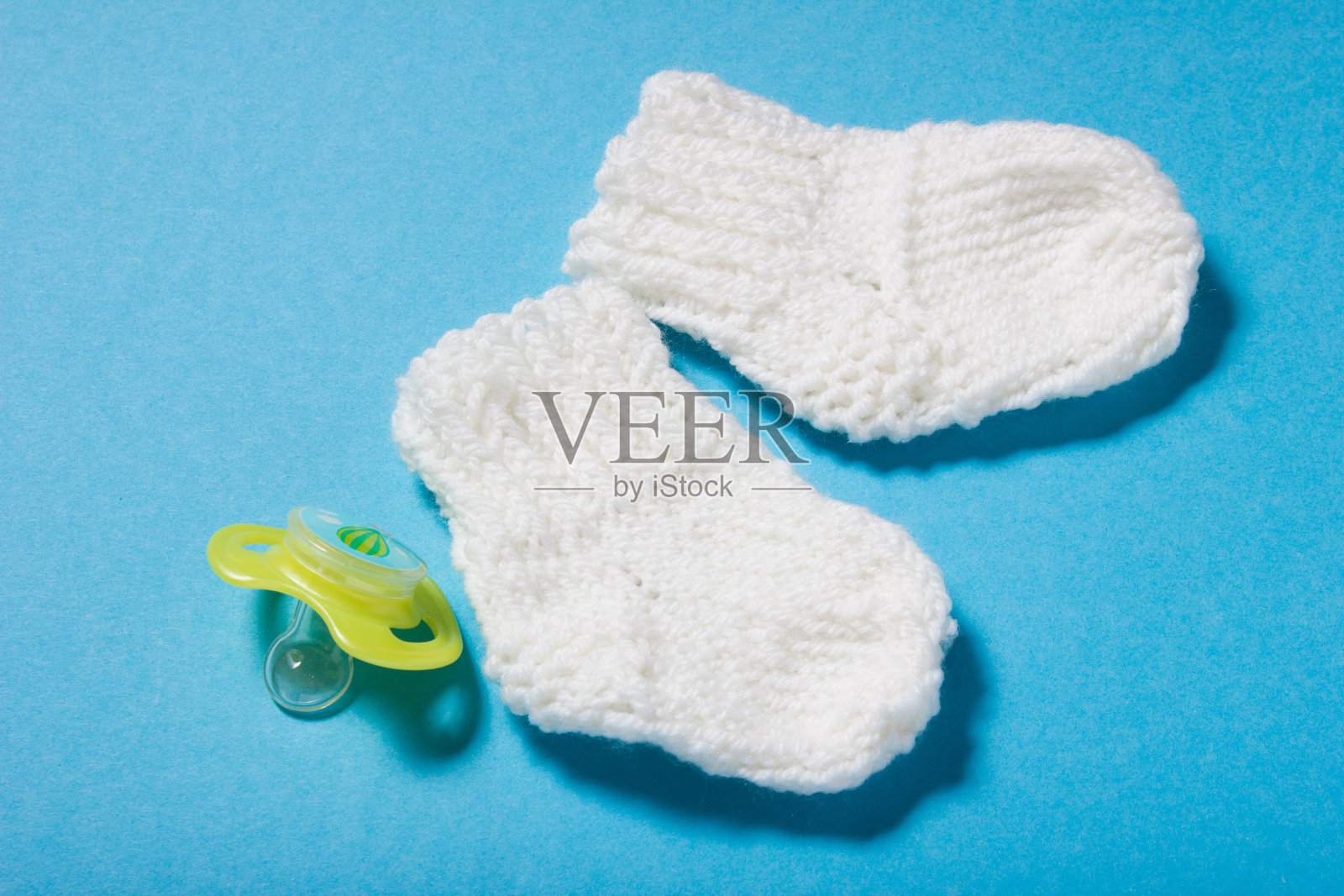 新生儿用手编织白色羊毛帽子和袜子。照片摄影图片