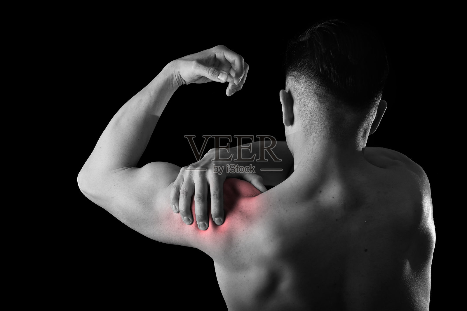 年轻的肌肉发达的运动员抱着疼痛的肩膀触摸照片摄影图片