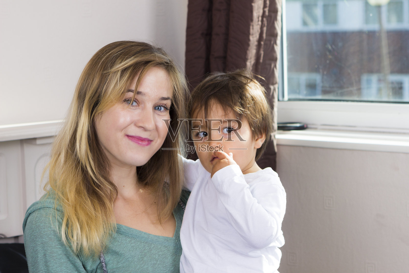 怀里抱着儿子的年轻女子照片摄影图片