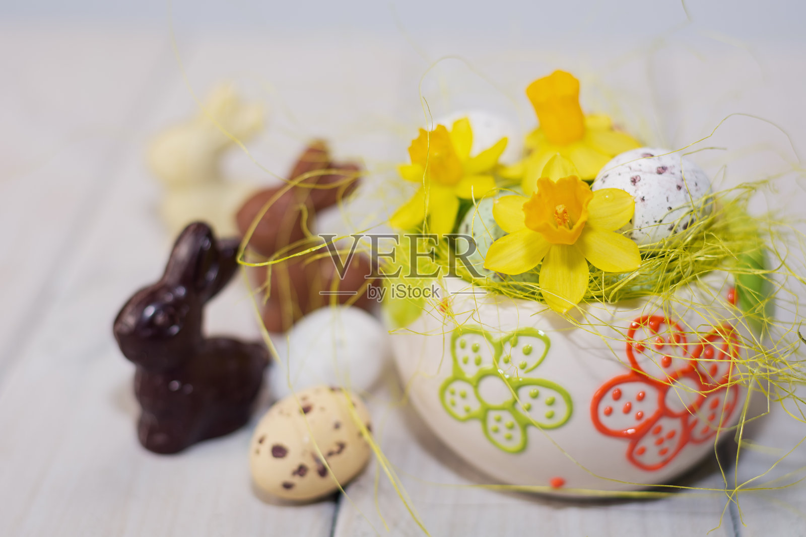 兔子，在巧克力蛋的装饰巢里装饰着水仙花。照片摄影图片