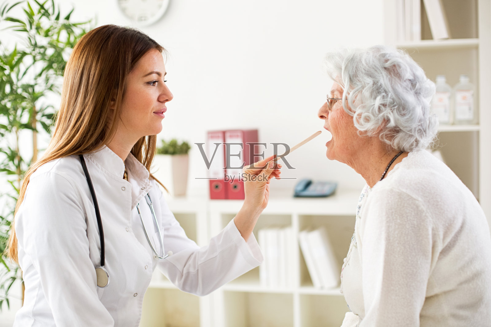 年轻漂亮的医生给老女人检查喉咙照片摄影图片